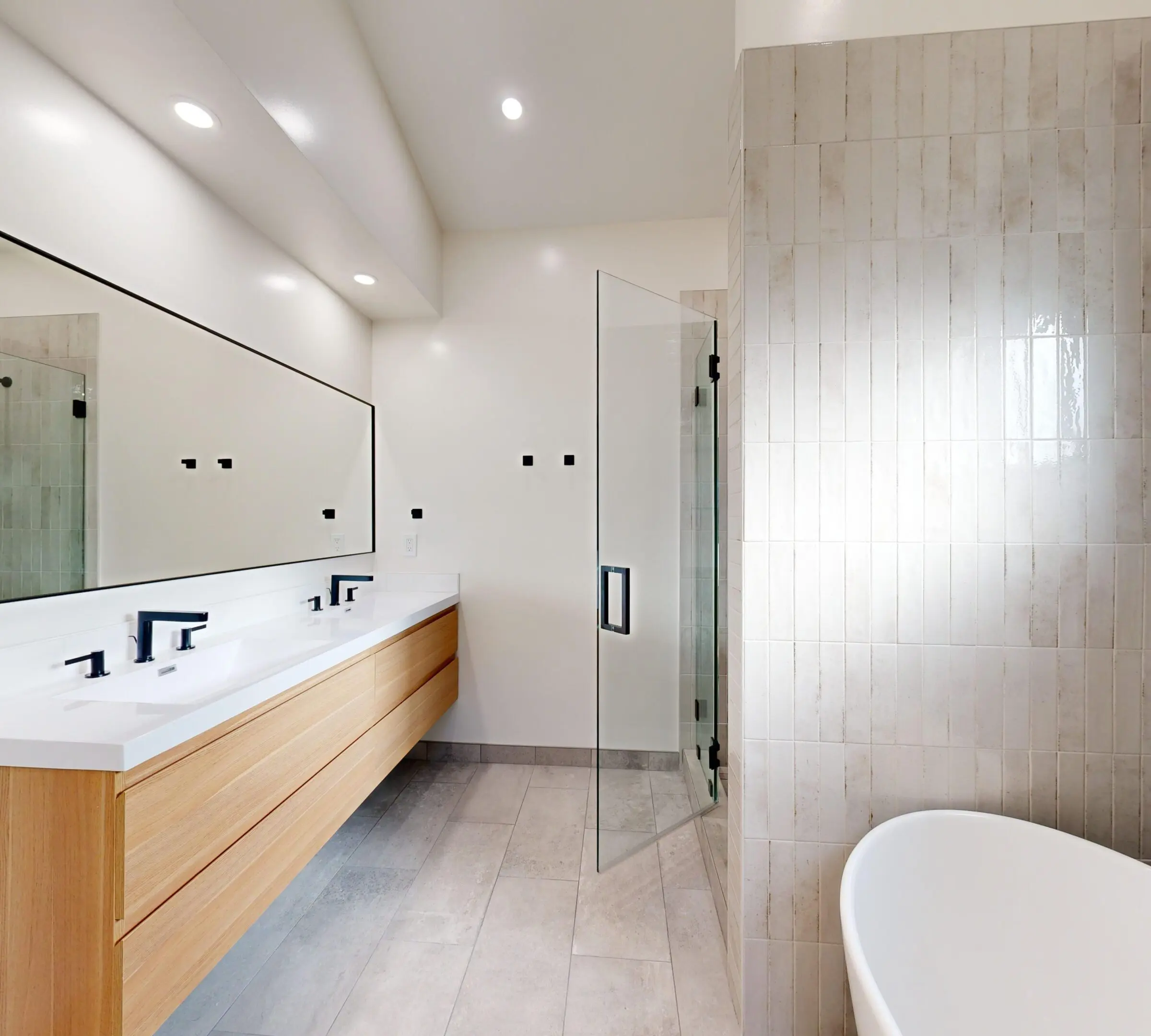 Modern bathroom with double sink, wooden vanity, and glass shower.